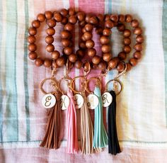 several wooden beads with tassels are arranged on a bed sheet and one has a personalized charm