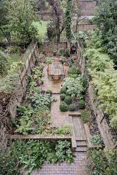 an aerial view of a garden with lots of green plants and small wooden tables in the center