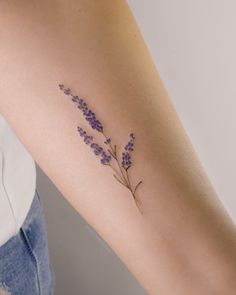 a woman's arm with a small lavender tattoo on the left side of her arm