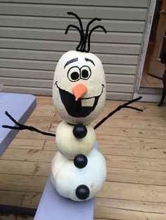 a snowman made out of plastic sitting on top of a wooden floor next to a building