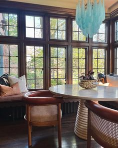 a dining room table and chairs in front of large windows