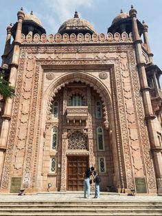 two people standing in front of an ornate building