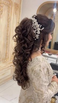 a woman is getting her hair done in a salon with long curls and flowers on her head