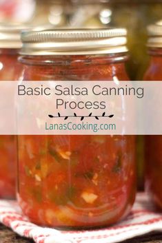 several jars filled with canned salsa sitting on top of a wooden table next to a red and white towel