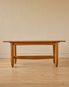 a wooden table sitting on top of a hard wood floor next to a white wall