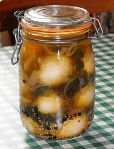 a glass jar filled with pickles sitting on top of a checkered table cloth