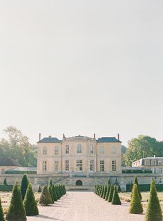 a large building with many trees in front of it and a walkway leading to the entrance