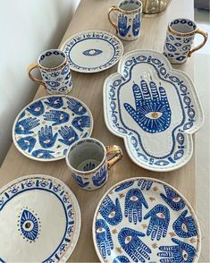 a table topped with lots of blue and white plates covered in handprinted designs