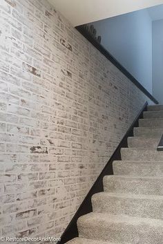 a laptop computer sitting on top of a table next to a stair case in front of a brick wall