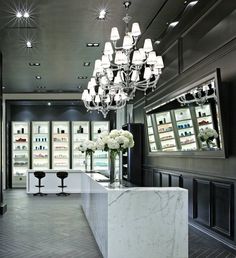 a large chandelier hangs from the ceiling above a counter with flowers in vases