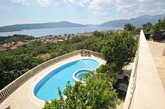 an aerial view of a swimming pool in the middle of trees and mountains behind it