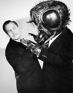 a black and white photo of a man in a suit with a creepy mask on his face