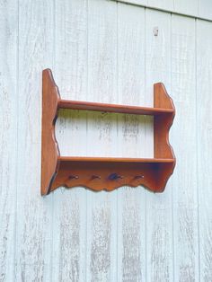 a wooden shelf mounted to the side of a white painted building with holes in it