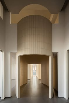 an empty hallway with white walls and beige tiles on the wall, leading to another room