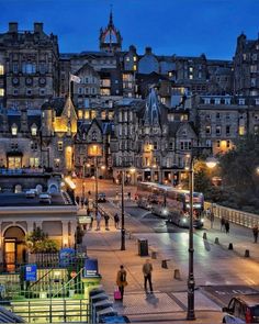 the city is lit up at night and people are walking around