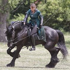 a woman riding on the back of a black horse