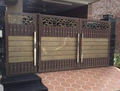 an iron gate is shown in front of a brick wall and door with decorative designs on it