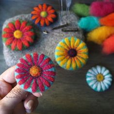 someone is holding up some colorful felt flowers