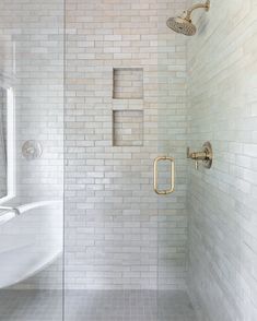 a walk in shower sitting next to a white bath tub under a faucet