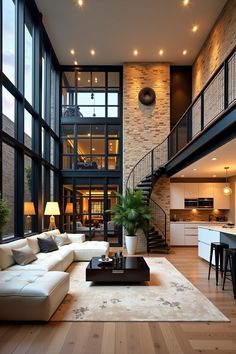 a living room filled with furniture and lots of windows next to a stair case in front of a kitchen