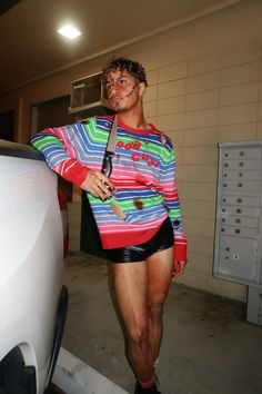 a man in shorts is standing next to a car with blood on his face and mouth