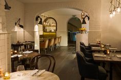 an empty restaurant with tables and chairs in front of the bar, along with candles on the table