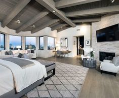 a large bedroom with wood floors and high ceilings has a fireplace in the corner, along with two couches on either side of the bed