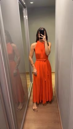 a woman in an orange dress taking a selfie