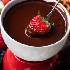 a chocolate fondant is garnished with a fresh strawberry on the top and served in a white bowl