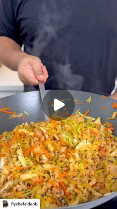 a man cooking vegetables in a wok with a large spatula on the side