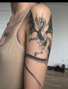 a woman's arm with a dragon tattoo on the left side of her body