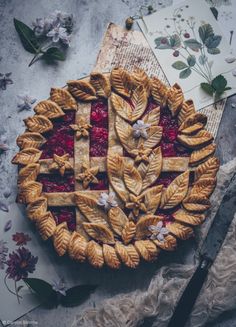 a pie sitting on top of a table next to a knife and napkin with flowers