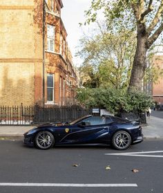 a blue sports car is parked on the side of the road in front of a brick building