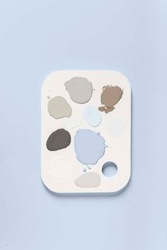 a palette with different shades of paint sitting on top of a blue surface, in front of a light blue background