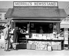 an old black and white photo of two people standing in front of a news stand