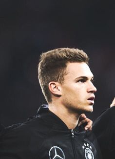 a soccer player is holding his hand up to the sideline while wearing a black jacket