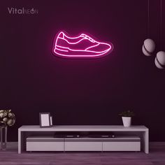 a neon pink shoe is on the wall next to a white table and vases