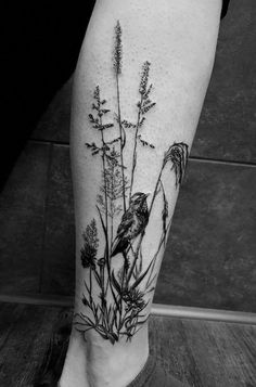 a black and white photo of a flower with a bird on it's leg