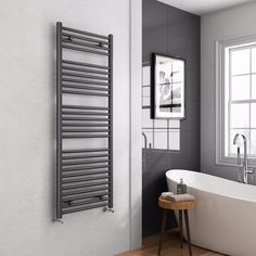 a white bath tub sitting next to a wall mounted radiator in a bathroom