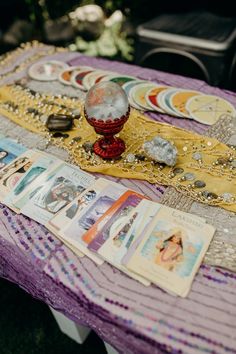 a table topped with lots of cards and other items on top of a purple table cloth