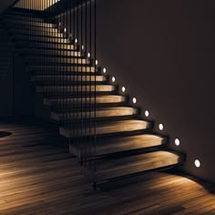 some lights that are on the side of a stair case in a room with wood floors