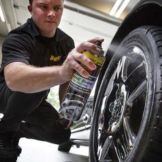 a man is working on a tire with a spray bottle and some tires in front of him