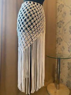 a white crocheted table lamp with fringes on it