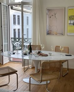 a dining room table with wine glasses and bottles on it in front of an open window