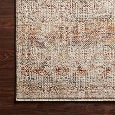 a brown and white rug on top of a wooden floor next to a vase with flowers