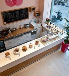 a bakery with lots of desserts on display in front of the counter and windows