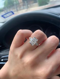 a woman's hand on the steering wheel of a car with an engagement ring