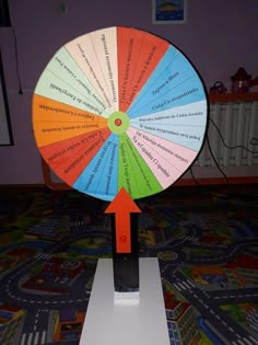 a colorful spinning wheel on top of a white stand with an arrow pointing to it