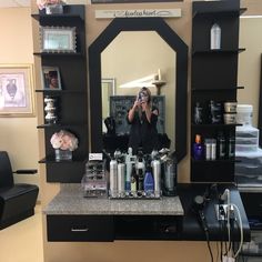 a woman taking a selfie in front of a hair salon mirror while she brushes her teeth