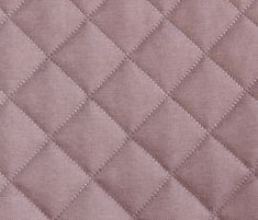 an upholstered quilted fabric with small squares in light pink color, closeup